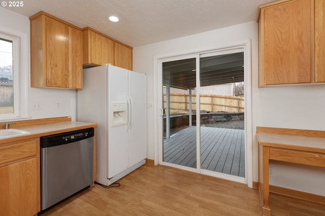 kitchen with white refrigerator with ice dispenser, light countertops, light wood-type flooring, stainless steel dishwasher, and recessed lighting