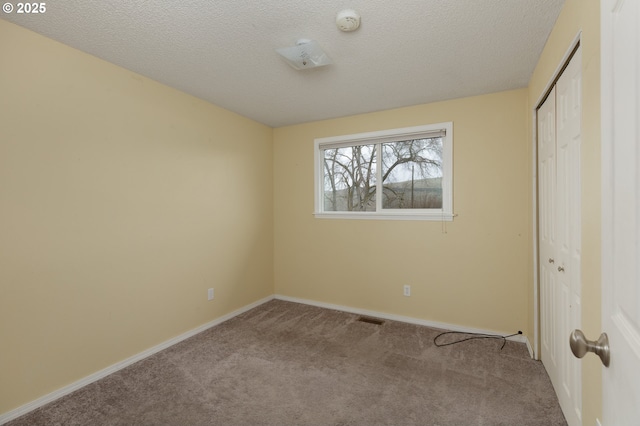 unfurnished bedroom with a textured ceiling, baseboards, a closet, and light colored carpet