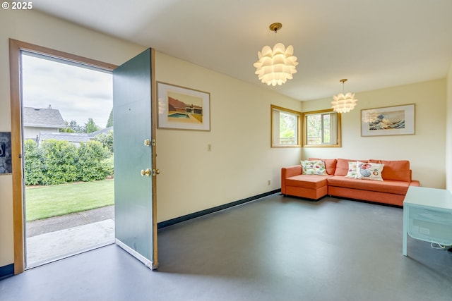 living room with baseboards, a notable chandelier, and finished concrete floors