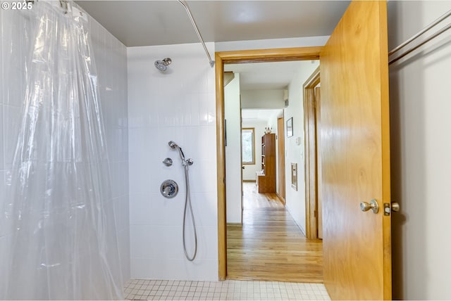 full bath featuring tiled shower and wood finished floors