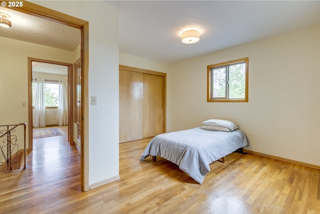 bedroom featuring baseboards, light wood finished floors, and a closet