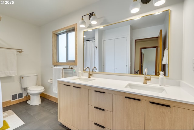 bathroom with a sink, toilet, double vanity, and visible vents