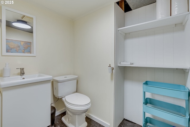 half bathroom with vanity, baseboards, and toilet