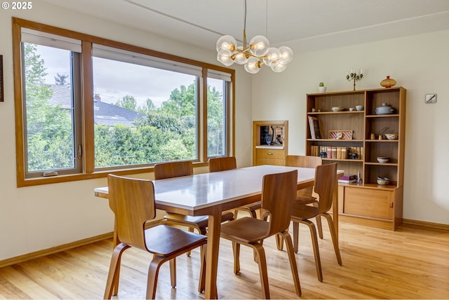 dining space featuring light wood-style floors, baseboards, and an inviting chandelier