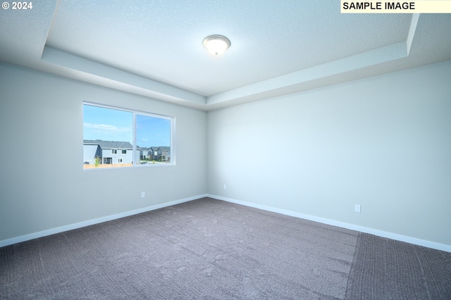 carpeted empty room with a tray ceiling and baseboards