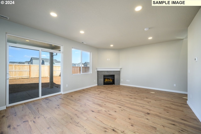 unfurnished living room featuring a tiled fireplace, wood finished floors, and recessed lighting