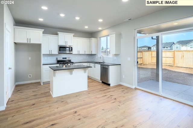 kitchen featuring stainless steel appliances, white cabinets, a sink, and visible vents