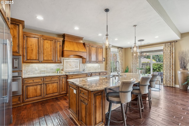kitchen featuring custom exhaust hood, brown cabinets, a sink, and stainless steel appliances