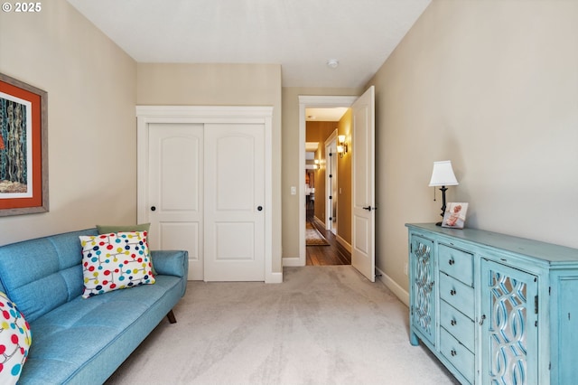 living area featuring light carpet and baseboards