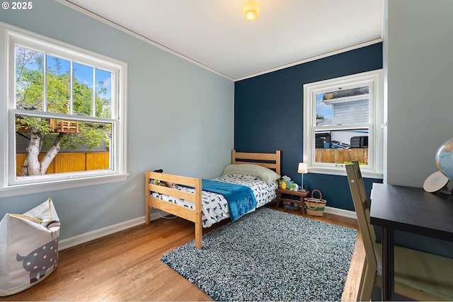 bedroom featuring baseboards, ornamental molding, and wood finished floors