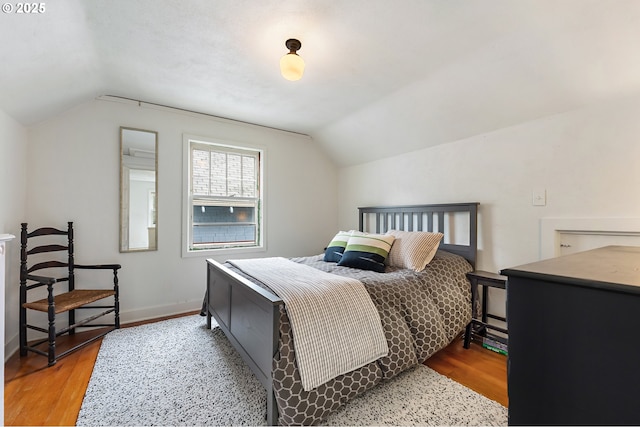bedroom with baseboards, vaulted ceiling, and wood finished floors