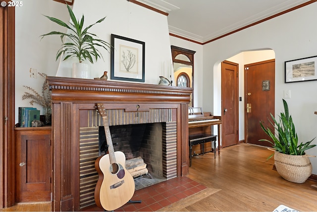 living area with arched walkways, wood finished floors, a fireplace, and ornamental molding