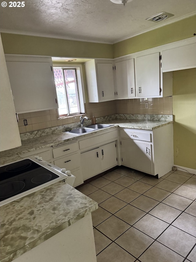 kitchen featuring white cabinets, visible vents, tasteful backsplash, and a sink