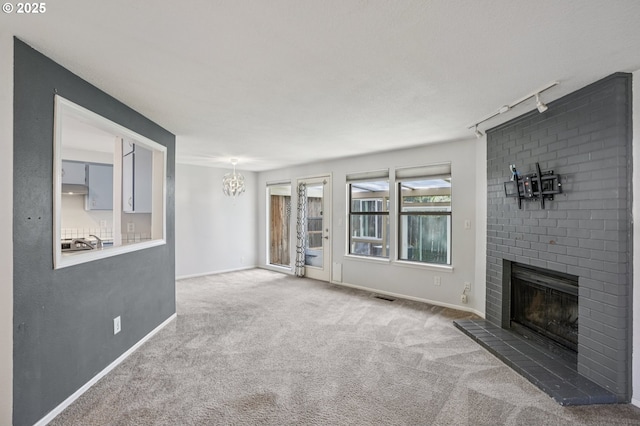 6250 SW 152nd Ave, Beaverton, OR 97007 - unfurnished living room featuring track lighting, carpet floors, a brick fireplace, and a chandelier