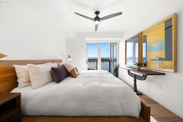 bedroom with baseboards, wood finished floors, a ceiling fan, and a water view