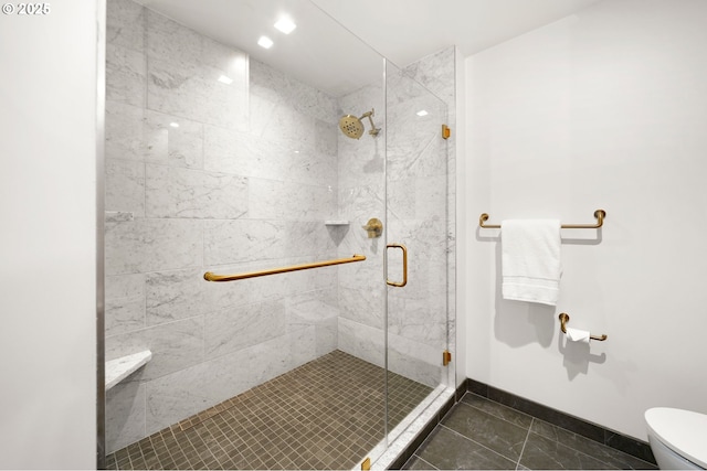 bathroom featuring baseboards, toilet, and a stall shower