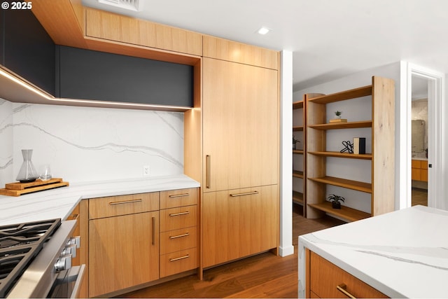 kitchen featuring light stone counters, wood finished floors, open shelves, range, and backsplash