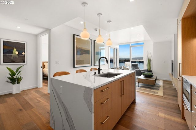 kitchen featuring recessed lighting, a kitchen island with sink, a sink, wood-type flooring, and modern cabinets