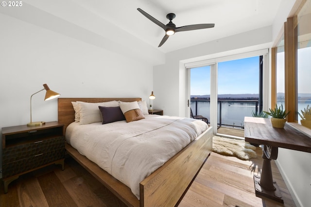 bedroom with access to exterior, baseboards, a water view, wood finished floors, and a ceiling fan