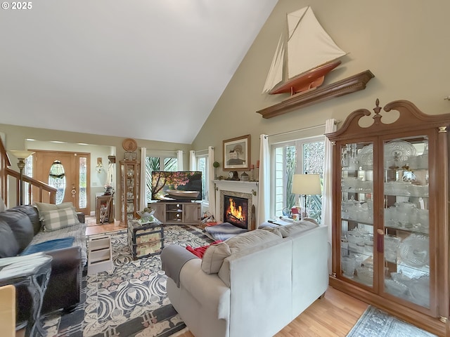 6931 Oakwood Ct, Brookings, OR 97415 - living room with a warm lit fireplace, stairway, high vaulted ceiling, and wood finished floors