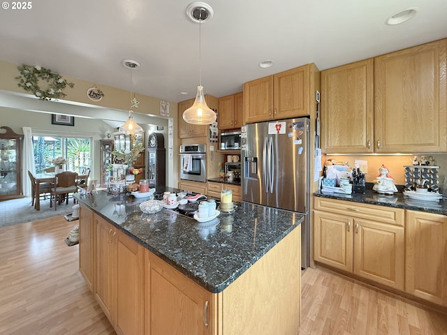 6931 Oakwood Ct, Brookings, OR 97415 - kitchen featuring dark stone countertops, light wood-style flooring, appliances with stainless steel finishes, and a kitchen island