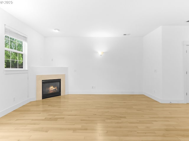 15235 SW Jasper Ln, Beaverton, OR 97007 - unfurnished living room with light wood-style flooring and a glass covered fireplace