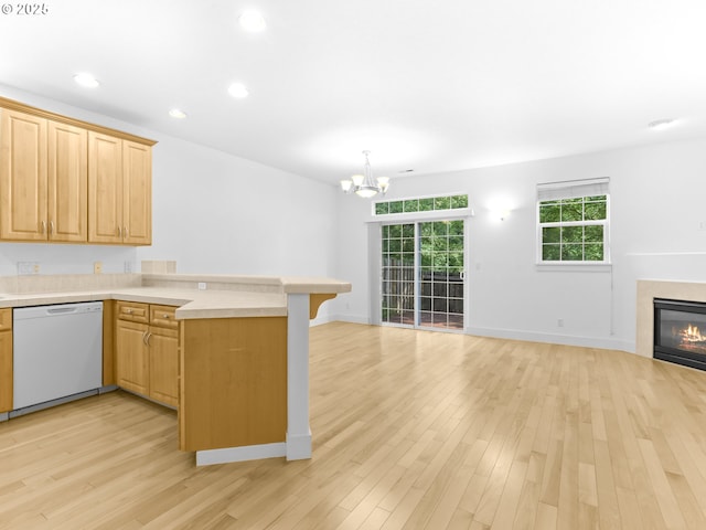 15235 SW Jasper Ln, Beaverton, OR 97007 - kitchen featuring dishwasher, a peninsula, light countertops, open floor plan, and a glass covered fireplace