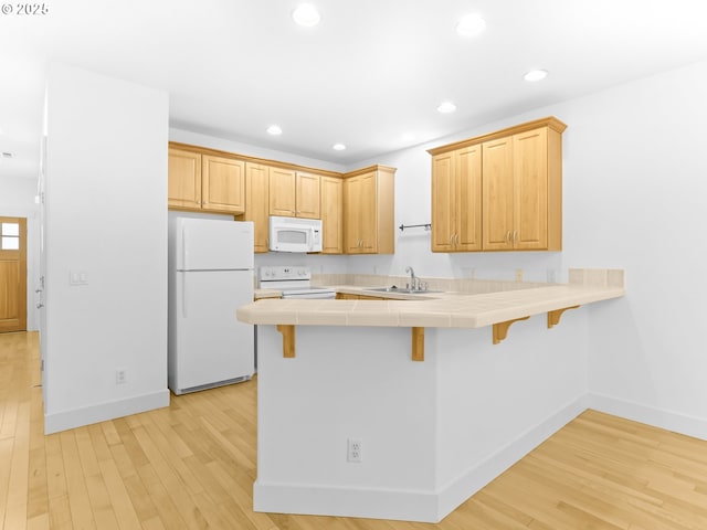 15235 SW Jasper Ln, Beaverton, OR 97007 - kitchen with white appliances, tile counters, a peninsula, a breakfast bar, and light wood-type flooring