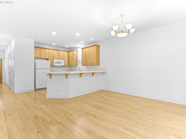 15235 SW Jasper Ln, Beaverton, OR 97007 - kitchen with white appliances, a chandelier, a kitchen bar, a peninsula, and light wood finished floors