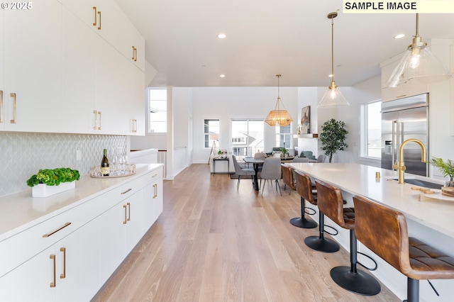 kitchen featuring light wood finished floors, light countertops, tasteful backsplash, and white cabinetry
