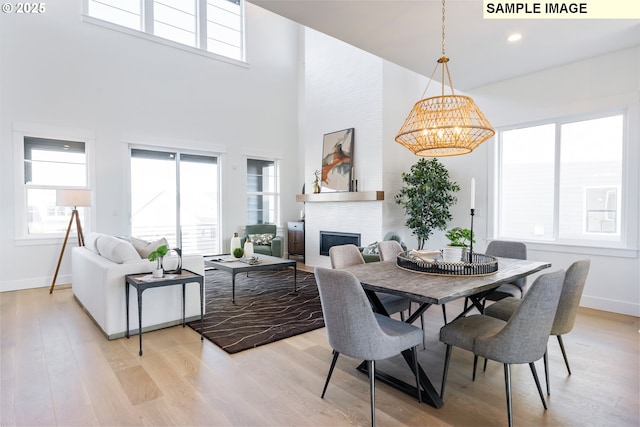 living area featuring wood finished floors, plenty of natural light, baseboards, a high ceiling, and recessed lighting