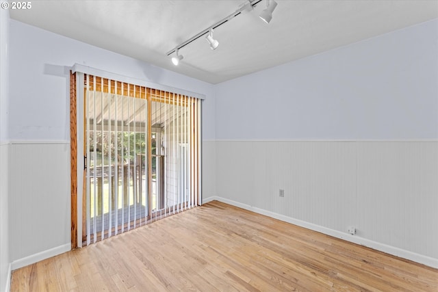 4912 N Yale St, Portland, OR 97203 - empty room featuring wood finished floors, track lighting, a wainscoted wall, and baseboards