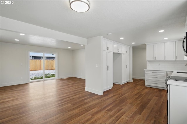 kitchen featuring electric stove, white cabinetry, dark wood-type flooring, and backsplash