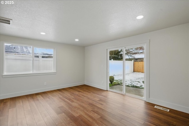 spare room featuring hardwood / wood-style flooring and a textured ceiling