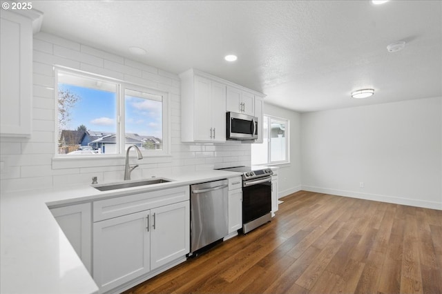 kitchen featuring sink, backsplash, white cabinetry, stainless steel appliances, and dark wood-type flooring