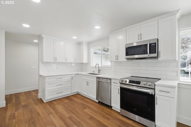 kitchen with white cabinetry, stainless steel appliances, light hardwood / wood-style floors, sink, and tasteful backsplash