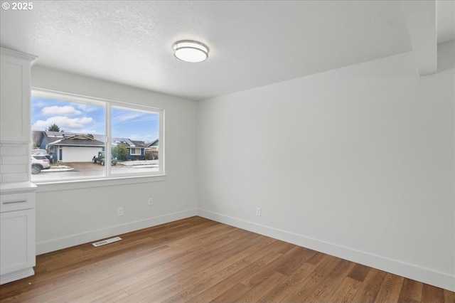 spare room featuring light hardwood / wood-style flooring and a textured ceiling