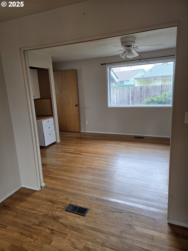 unfurnished room featuring baseboards, visible vents, ceiling fan, and light wood-style flooring