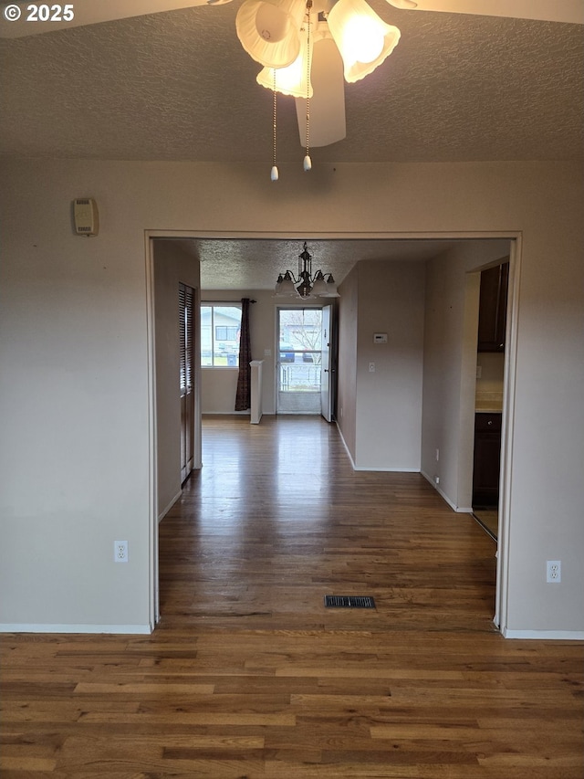 unfurnished dining area featuring baseboards, visible vents, dark wood-style floors, and a textured ceiling