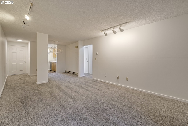 carpeted spare room with track lighting, a baseboard heating unit, and a textured ceiling