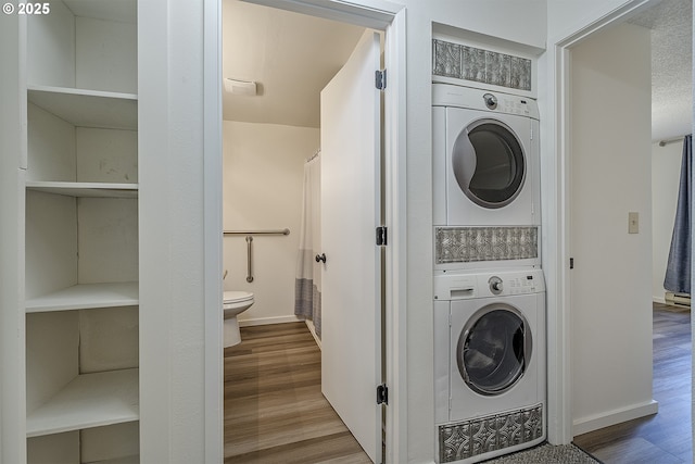 washroom featuring stacked washer / dryer and wood-type flooring