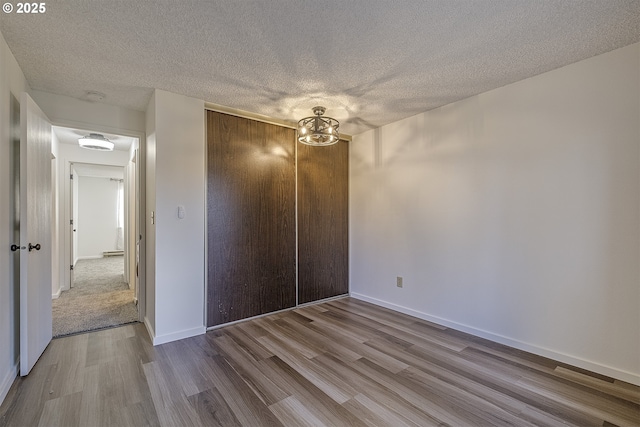 unfurnished bedroom featuring a textured ceiling, a closet, and light wood-type flooring