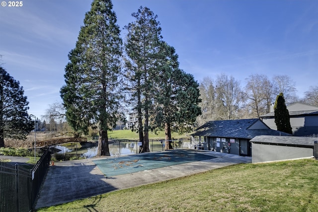 view of swimming pool featuring a water view, a yard, and a patio area