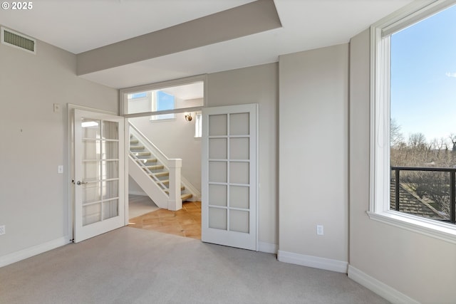 unfurnished room featuring plenty of natural light, light colored carpet, and french doors