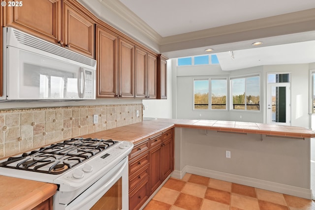 kitchen with white appliances, tasteful backsplash, ornamental molding, tile countertops, and kitchen peninsula