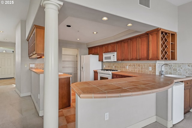 kitchen featuring sink, tile counters, kitchen peninsula, white appliances, and decorative columns