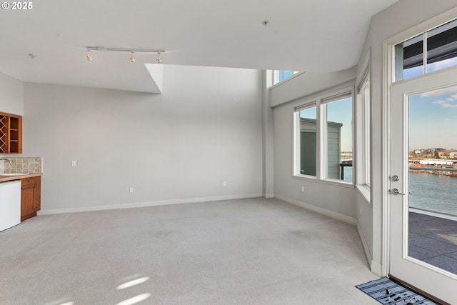 unfurnished living room with sink, light colored carpet, and a water view