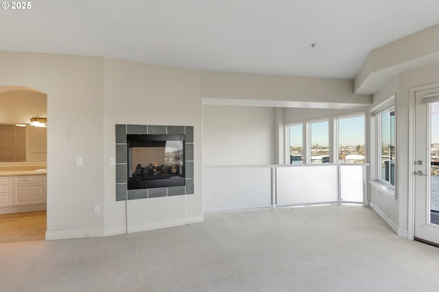 unfurnished living room featuring light colored carpet and a tile fireplace