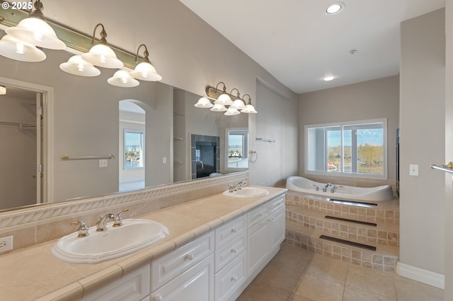 bathroom featuring vanity, a relaxing tiled tub, and tile patterned floors