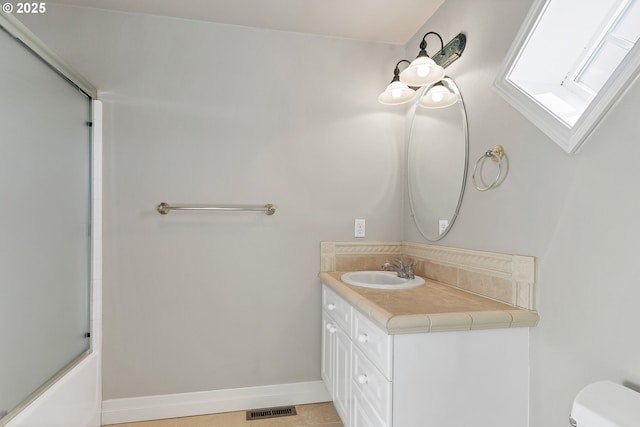 full bathroom featuring vanity, tile patterned floors, combined bath / shower with glass door, and toilet